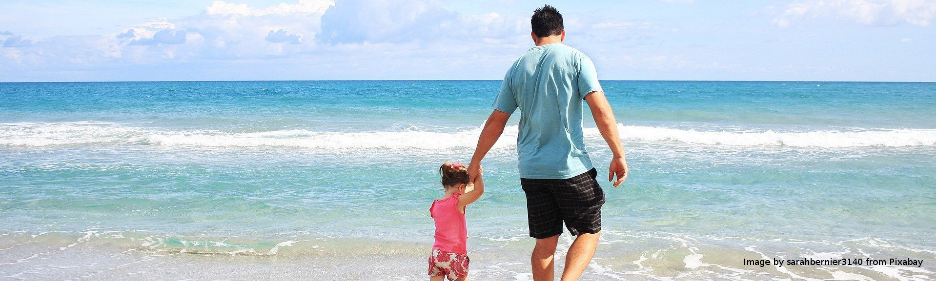 Vater mit kleiner Tochter am Strand spazierend
